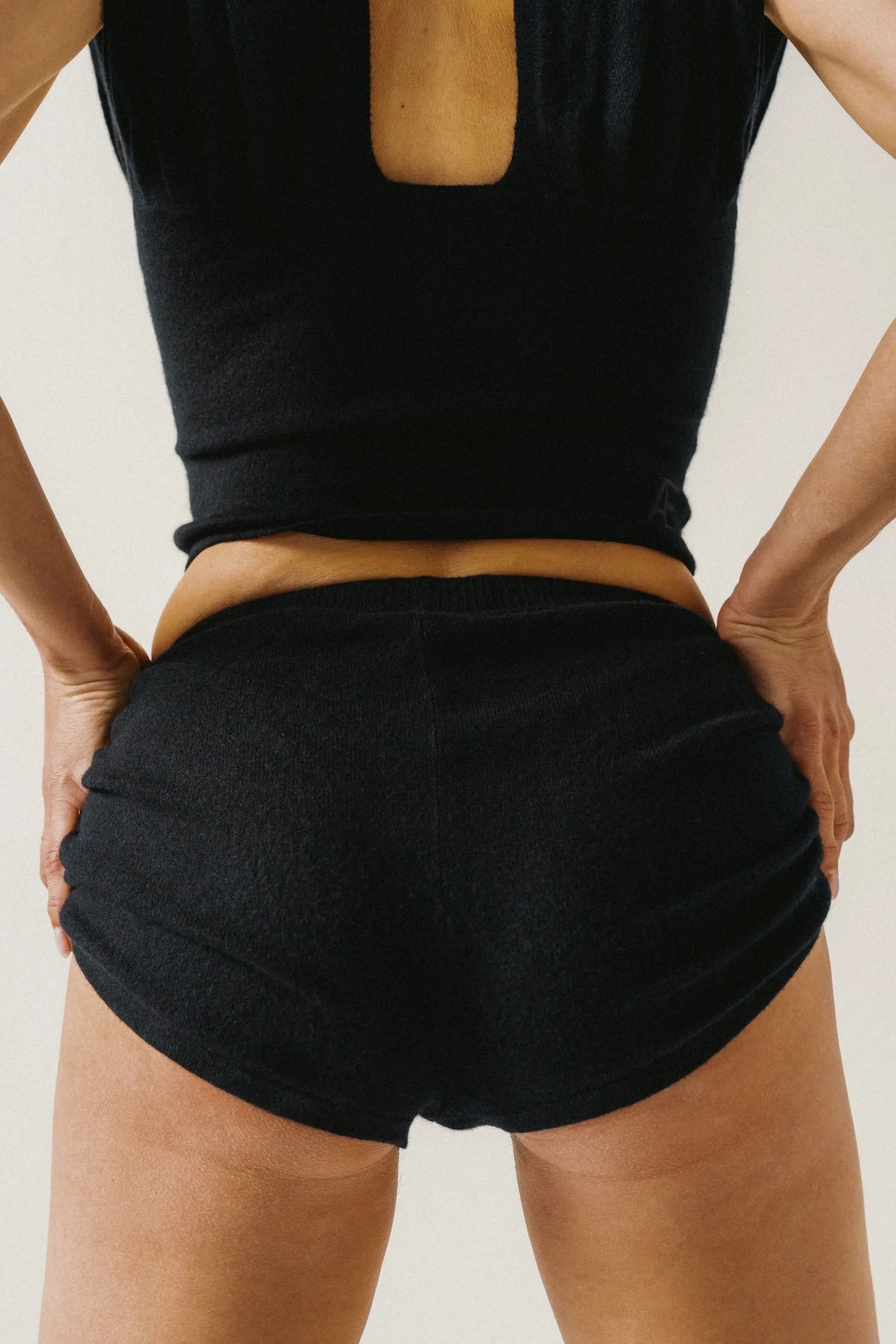 Woman wearing black cahsmere shorts and top on a plain background