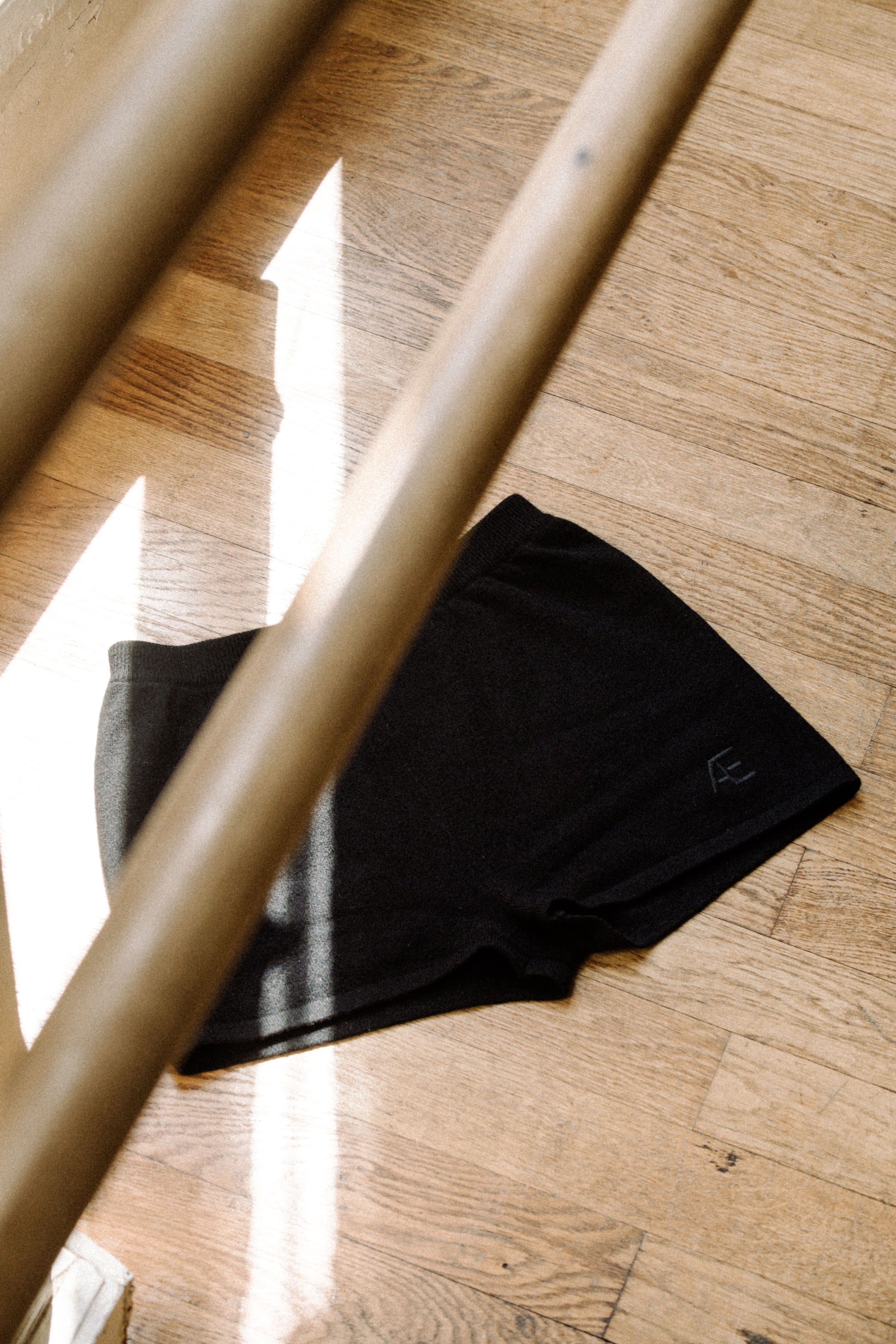 Black shorts with embroidered logo laid on a dance studio floor