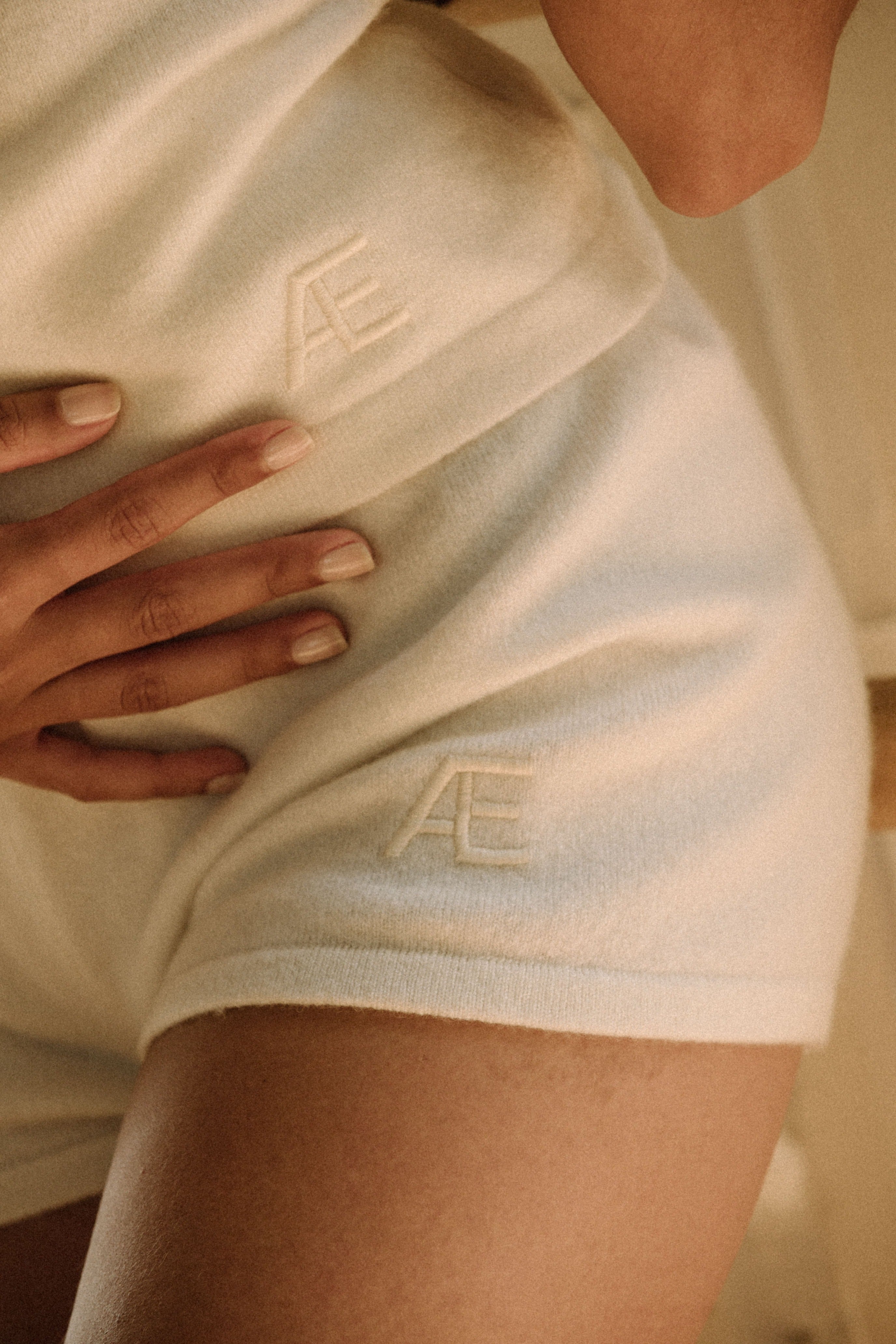 Close-up of a woman wearing an ivory mini shorts, focusing on the logo.