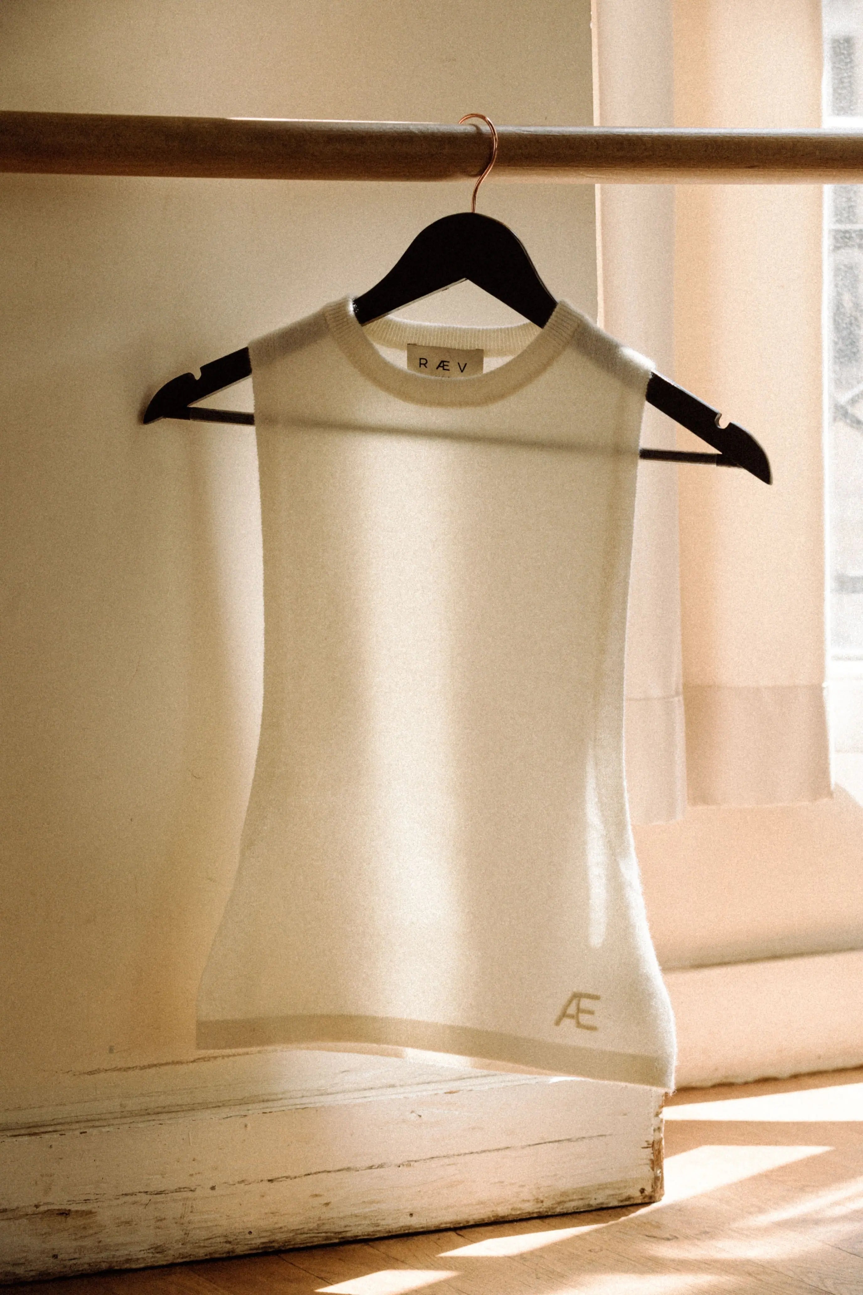 Ivory tank top on a hanger with 'AE' logo against a neutral background