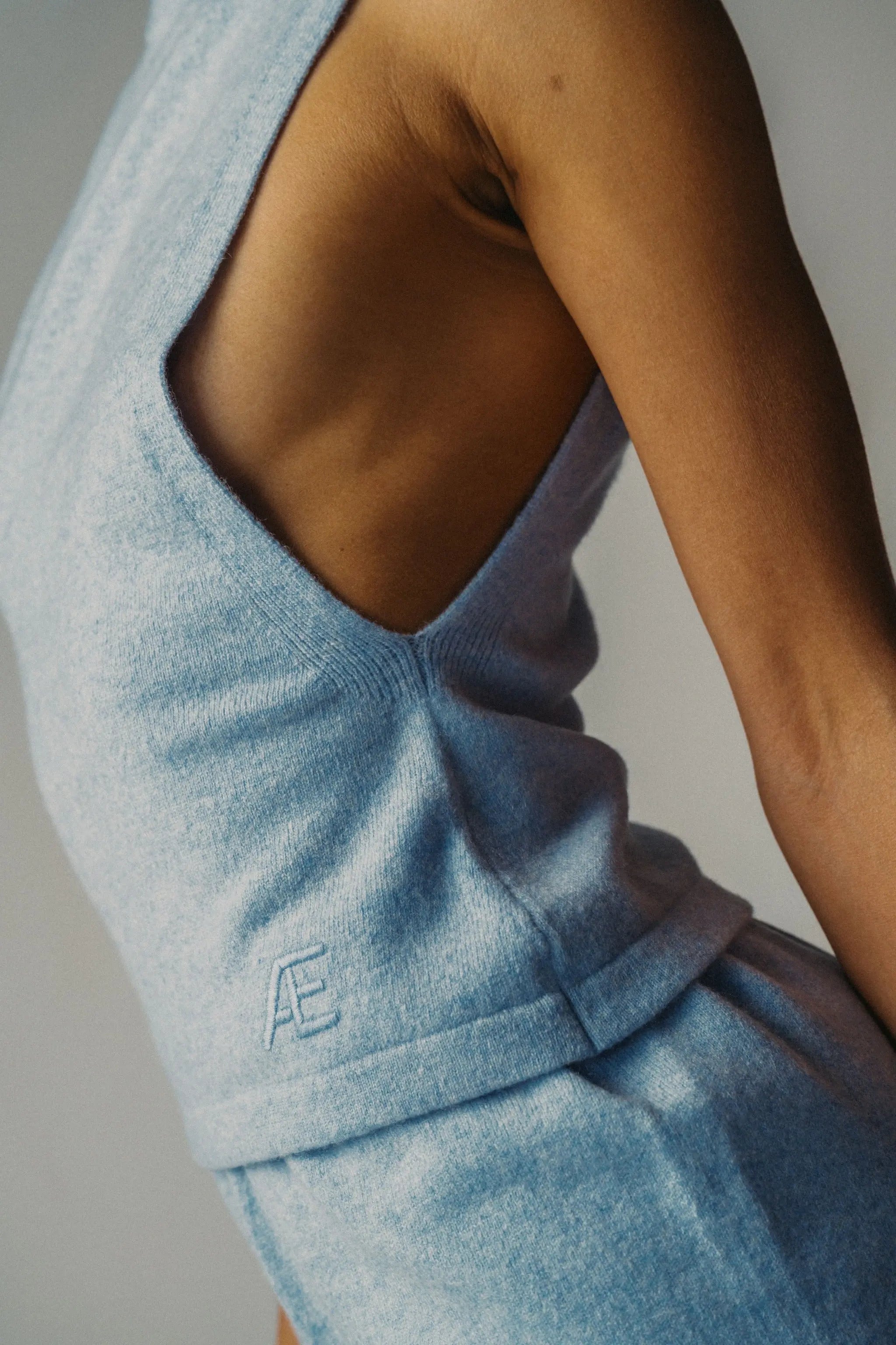 Woman wearing a light blue sleeveless top with embroidered detail
