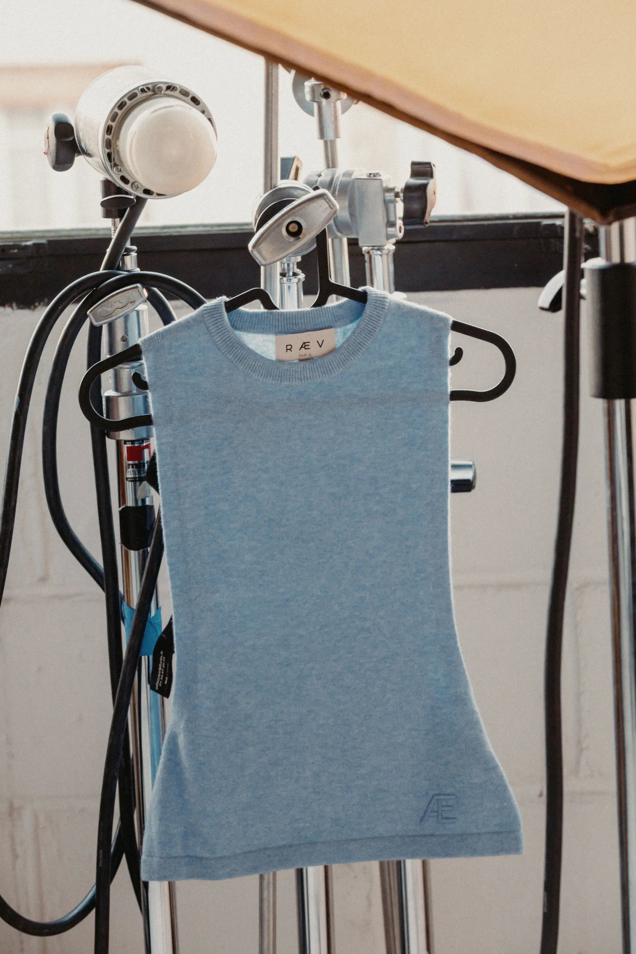Blue sleeveless tank top on a hanger in a studio background